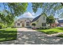 Charming brick home featuring lush landscaping, mature trees, and ample driveway space at 5940 Chapmans Trl, Carmel, IN 46033