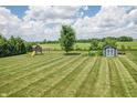 Large, well-maintained backyard featuring a playhouse and a shed, perfect for outdoor activities at 6702 W Willow Grove Dr, New Palestine, IN 46163