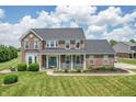 Charming brick home featuring a cozy front porch, lush lawn, and manicured landscaping at 6702 W Willow Grove Dr, New Palestine, IN 46163