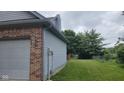 Side view of the home showcasing light blue siding, a brick facade, and a well-maintained grassy lawn at 7168 Camwell Dr, Indianapolis, IN 46268