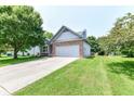 Well-maintained home with a two-car garage, a lush green lawn, and mature trees at 7168 Camwell Dr, Indianapolis, IN 46268