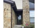 Close up of front door featuring stone facade, flower bed, and front storm door at 7950 Eagle Valley Pass, Indianapolis, IN 46214