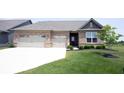 Charming brick home boasts a well-manicured lawn, two-car garage, and inviting front entrance at 9671 Holborn Ave, McCordsville, IN 46055