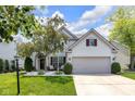 Inviting front yard with mature trees, landscaping, and a cozy seating area by the front door at 10215 Lauren Pass, Fishers, IN 46037
