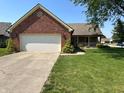 Charming brick home with a well-manicured lawn, mature trees, and a two-car garage at 10976 Mt Vernon N Trl, Indianapolis, IN 46229