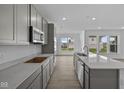 Modern kitchen with gray cabinets, stainless steel appliances, quartz countertops, and sleek finishes, offering a stylish cooking space at 12490 Morning Ridge Way, Noblesville, IN 46060