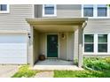 Inviting covered front porch with neutral siding, stylish lighting fixtures, and green door at 1252 Jasmine Dr, Greenfield, IN 46140