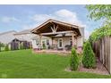 A large, covered patio with ample seating, a landscaped yard, and partial fencing defines this backyard at 12535 Old Pond Rd, Noblesville, IN 46060