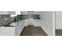 Bright kitchen featuring white cabinets, granite countertops, and decorative tile backsplash at 1409 N Grant Ave, Indianapolis, IN 46201