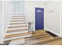 Inviting foyer with wood-look floors, painted staircase, and blue front door at 1910 W 10Th St, Anderson, IN 46016