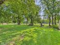 Expansive green back yard with mature shade trees and white fencing in the distance at 2126 Tartan Rd, Anderson, IN 46012