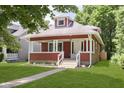 Inviting red two-story home with a classic craftsman architectural style, front porch, and well-maintained lawn at 4226 Cornelius Ave, Indianapolis, IN 46208