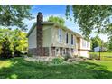 The side view of this split-level home shows the large brick chimney and landscaped yard at 586 Shady Creek Dr, Greenwood, IN 46142