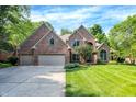 Charming brick home boasts a manicured lawn, mature trees, and a three-car garage, perfect for Gathering living at 7648 W Williamswood Dr, New Palestine, IN 46163