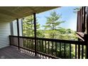 View from covered deck with wooden railing overlooking mature trees and foliage at 8176 Shorewalk Dr # C, Indianapolis, IN 46236
