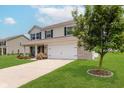 Charming home featuring well-manicured lawn, attached garage, and beautiful landscaping, complemented by a lush green tree at 985 Farmington Trl, Brownsburg, IN 46112