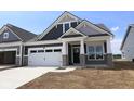New construction exterior showcasing a two-car garage, gray siding, stone accents, and a well-manicured lawn under a clear blue sky at 12516 Morning Ridge Way, Noblesville, IN 46060