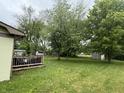 Spacious backyard with grass and trees with a view of the deck, providing a private and serene outdoor space at 1308 Phillips Dr, Indianapolis, IN 46241