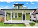 Eye-catching green home with a modern black door and a charming covered front porch at 1338 N Parker Ave, Indianapolis, IN 46201