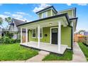 Inviting green home featuring a classic covered front porch with white columns and black trim at 1338 N Parker Ave, Indianapolis, IN 46201