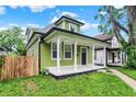Lovely green house featuring a covered front porch with elegant white columns and nice landscaping at 1338 N Parker Ave, Indianapolis, IN 46201