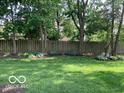 Lush green backyard with mature trees and a wooden fence providing privacy at 1419 Dominion Dr, Zionsville, IN 46077