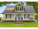 Attractive view of the house exterior featuring a blue door, front porch, and well-manicured landscaping at 14855 E State Road 46, Columbus, IN 47203