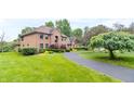 Two-story brick home featuring a curved driveway and beautifully landscaped front yard under a cloudy sky at 1497 N 200 W, Greenfield, IN 46140