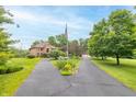 A two-story brick home has a circular driveway with an American flag and lush landscaping on an expansive lawn at 1497 N 200 W, Greenfield, IN 46140
