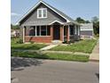 Inviting gray house featuring brick accents, a front porch, and well-maintained landscaping at 1501 California St, Columbus, IN 47201