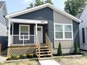Charming home showcasing dark blue and tan siding and a quaint porch with white railings and wooden stairs at 1628 Spann Ave, Indianapolis, IN 46203