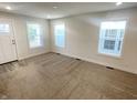 Bright living room featuring neutral carpet, white walls, and natural light through three windows at 1628 Spann Ave, Indianapolis, IN 46203
