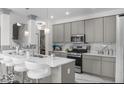 Modern kitchen featuring gray cabinets, quartz countertops, stainless steel appliances, and an island with bar seating at 210 Lynnette Way, Cumberland, IN 46229