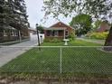 Charming single story home featuring a well-manicured lawn and a chain link fence at 2411 Harlan St, Indianapolis, IN 46203