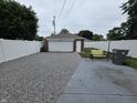 View of detached garage with concrete and gravel driveway, bench, and privacy fence at 2411 Harlan St, Indianapolis, IN 46203