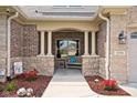 Inviting front porch with stone and brick accents, featuring a cozy bench and decorative landscaping at 5194 Orahood Ct, Plainfield, IN 46168