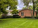 A green lawn surrounds this well-kept home with mature trees and manicured bushes, adding to its curb appeal at 7038 E 65Th St, Indianapolis, IN 46256