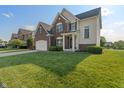 Inviting two-story home with lush green lawn, showcasing brick facade and attached two-car garage at 7356 Woodington Pl, Indianapolis, IN 46259