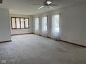 Spacious living room with carpet, light walls, ceiling fan, and multiple windows with sheer curtains at 806 S Jefferson St, Brownsburg, IN 46112