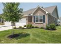 Attractive home with a well-kept lawn, brick facade, complemented by a young tree and manicured landscaping at 8842 Twain Ln, Indianapolis, IN 46239