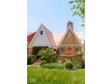 Well-maintained brick home with a unique roof, covered porch, and beautifully landscaped garden area at 972 N Audubon Rd, Indianapolis, IN 46219