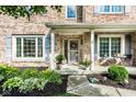 Charming brick home entrance with gray shutters, decorative plants, and a welcoming porch at 9740 Logan Ln, Fishers, IN 46037