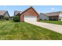 Close-up of a two-car garage on a brick home with a green lawn and landscaping at 10938 E Mount Vernon N Trl, Indianapolis, IN 46229