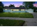Charming single-story home with a well-manicured lawn and detached two-car garage at dusk at 11 Sayre Dr, Greenwood, IN 46143