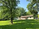 Spacious backyard of home with deck overlooking manicured lawn and shady mature trees at 1219 Lansdowne Rd, Indianapolis, IN 46234