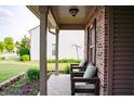 Inviting front porch with brick detail, porch chairs, and view of front yard at 1242 Flatrock Dr, Anderson, IN 46013