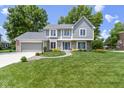 Well-maintained two-story home with a lush green lawn and mature trees providing ample shade at 15120 Romalong Ln, Carmel, IN 46032