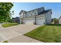View of a two-story home with gray siding, a well-manicured lawn, and a three-car garage at 15736 Conductors Dr, Westfield, IN 46074