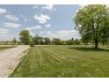 Expansive green backyard with a gravel area, bordered by mature trees and a distant basketball hoop at 2170 N Old State Road 9, Columbus, IN 47203