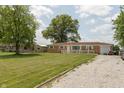 Inviting single-story brick home with a spacious, well-kept lawn, gravel driveway and convenient attached garage at 2170 N Old State Road 9, Columbus, IN 47203
